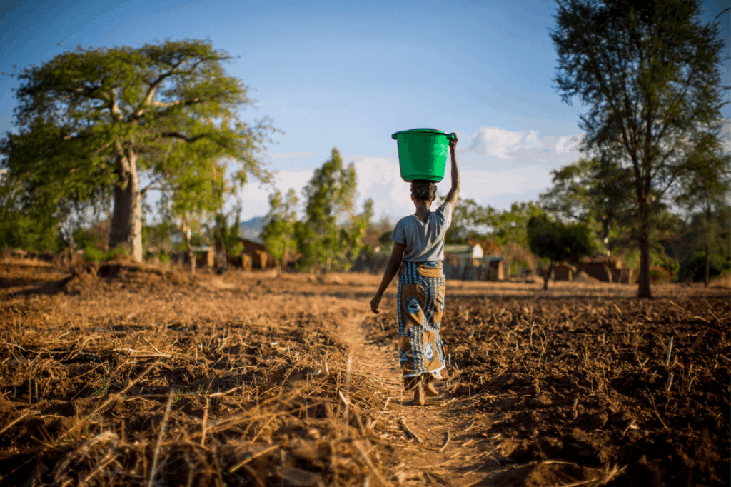 Lady walking through village with water