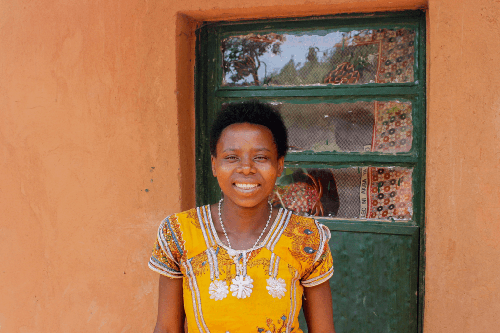 Woman smiling at the camera outside her house in Rwanda